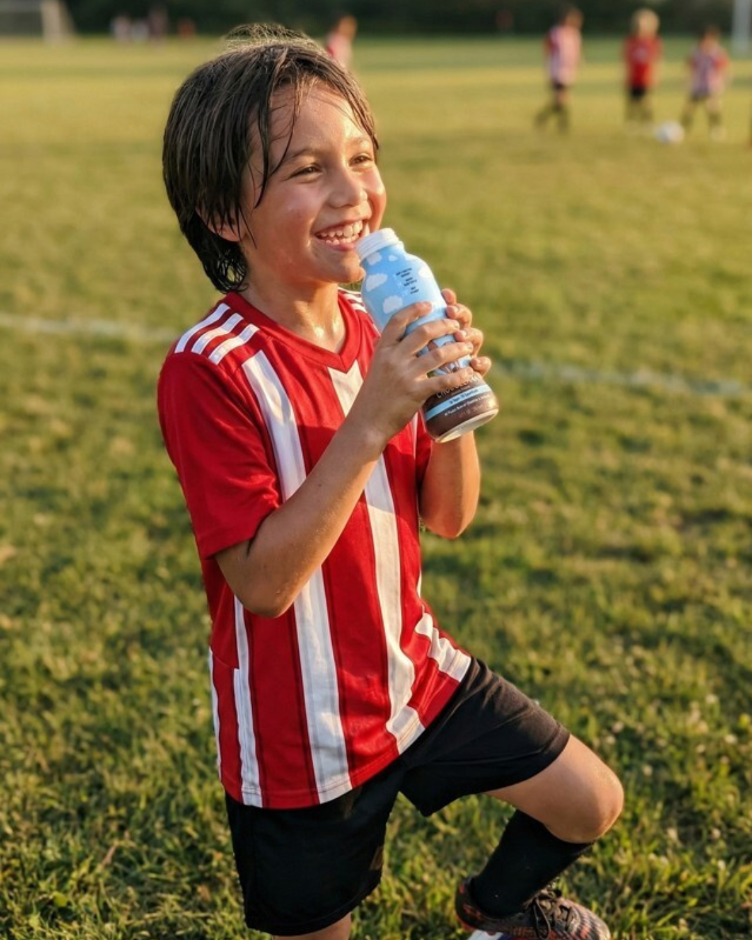 Kid drinking Ummy on soccer field